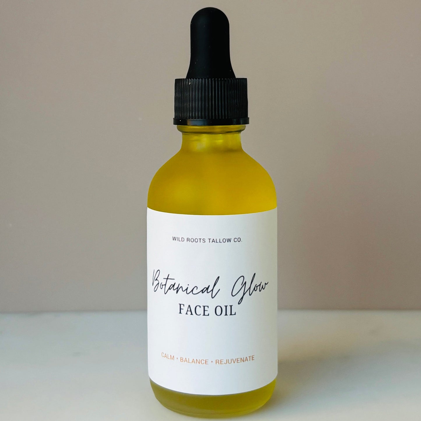 Bottle of Botanical Glow Face Oil with dropper on a neutral background