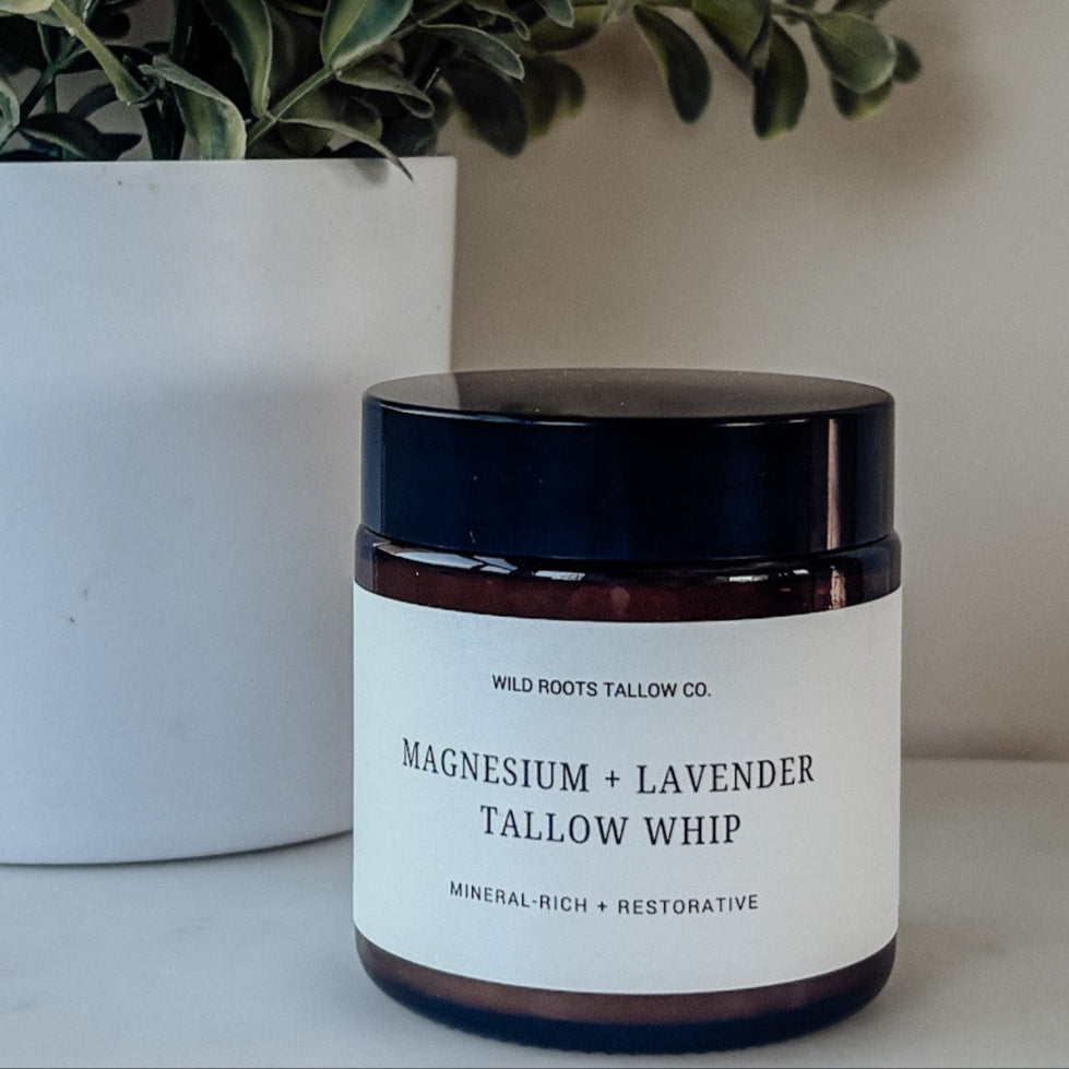 Jar of magnesium and lavender tallow whip next to a potted plant on a marble surface.