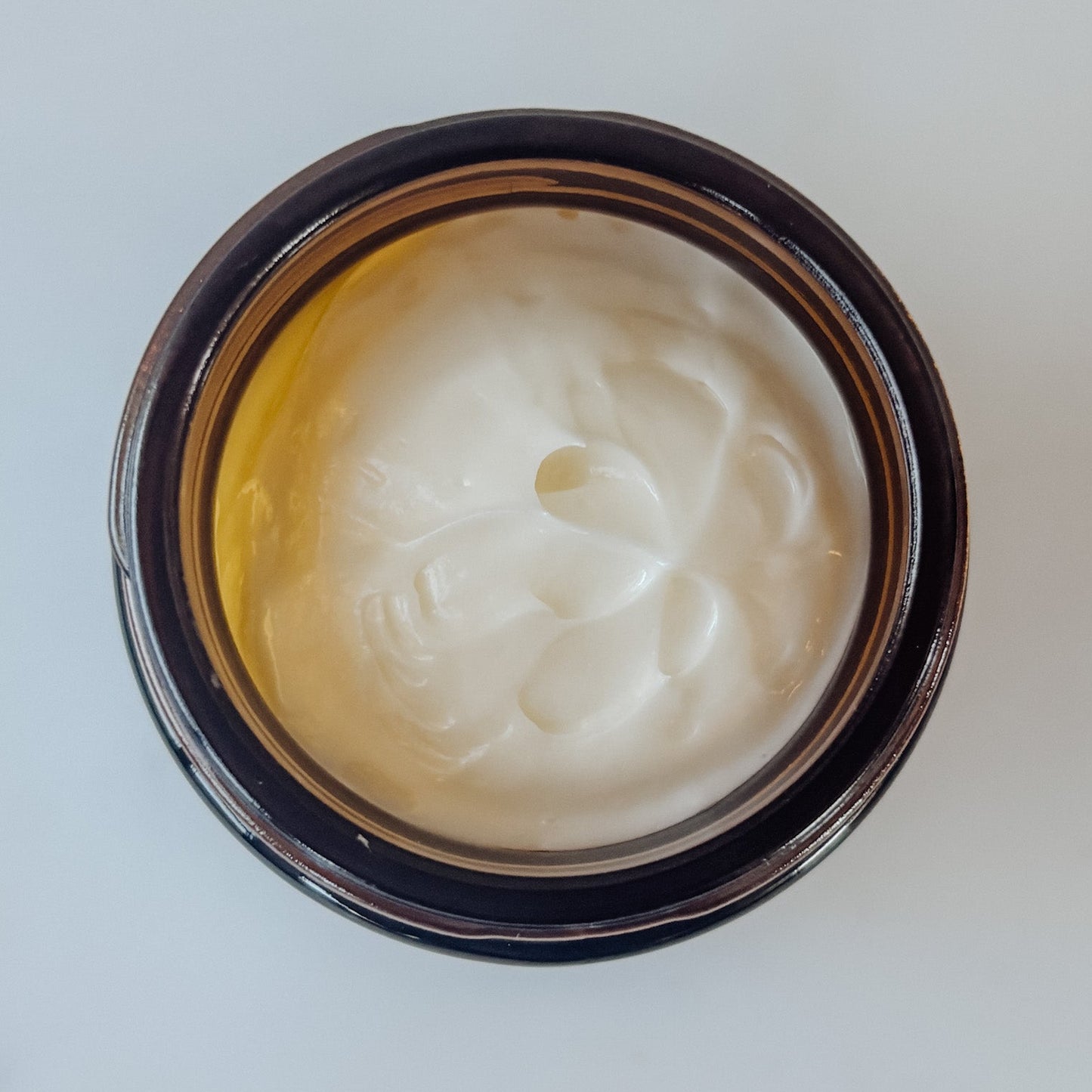 Jar of white cream on a light gray background