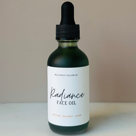 Bottle of Radiance Face Oil with a dropper on a neutral background