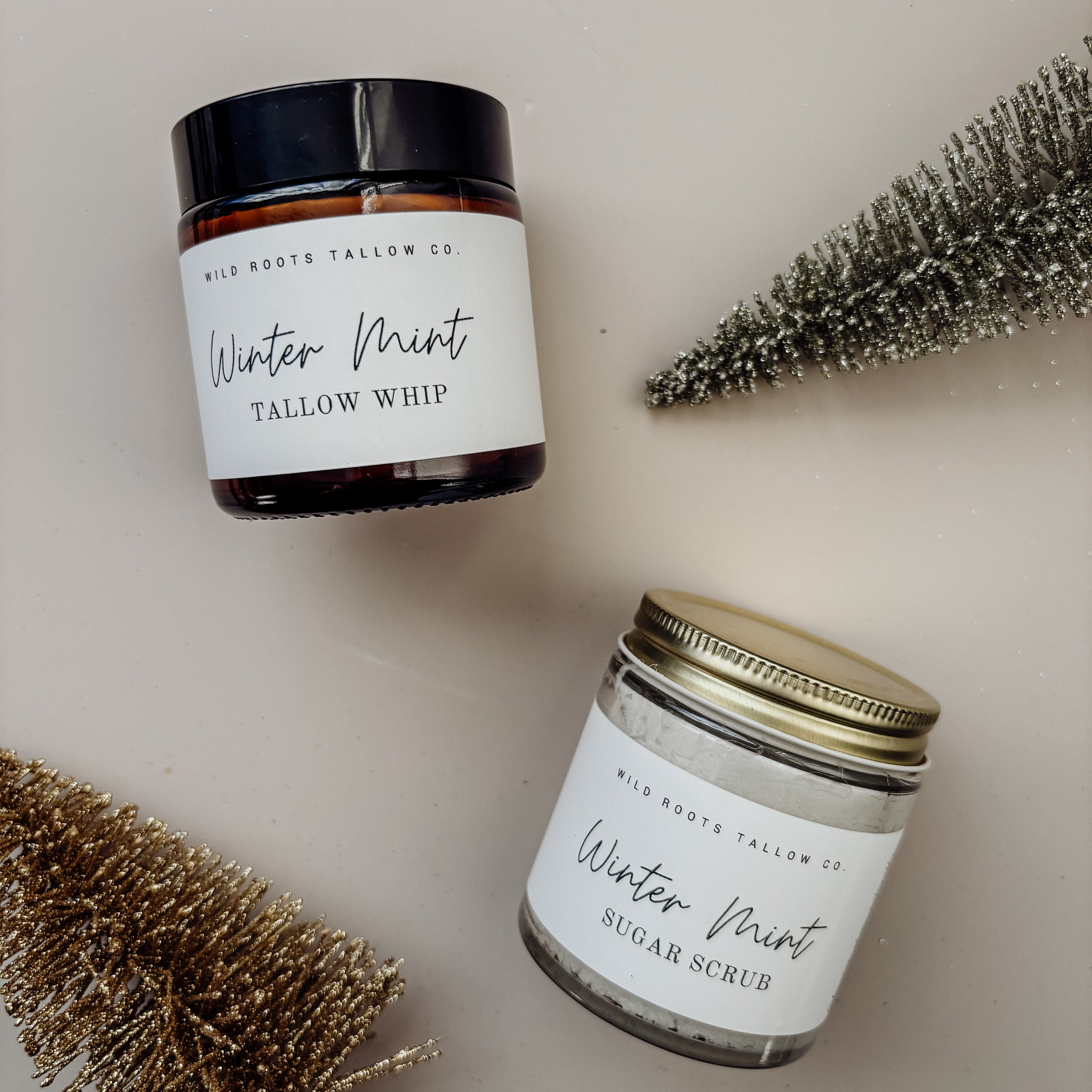 Two jars of 'Winter Mint' products with decorative branches on a neutral background