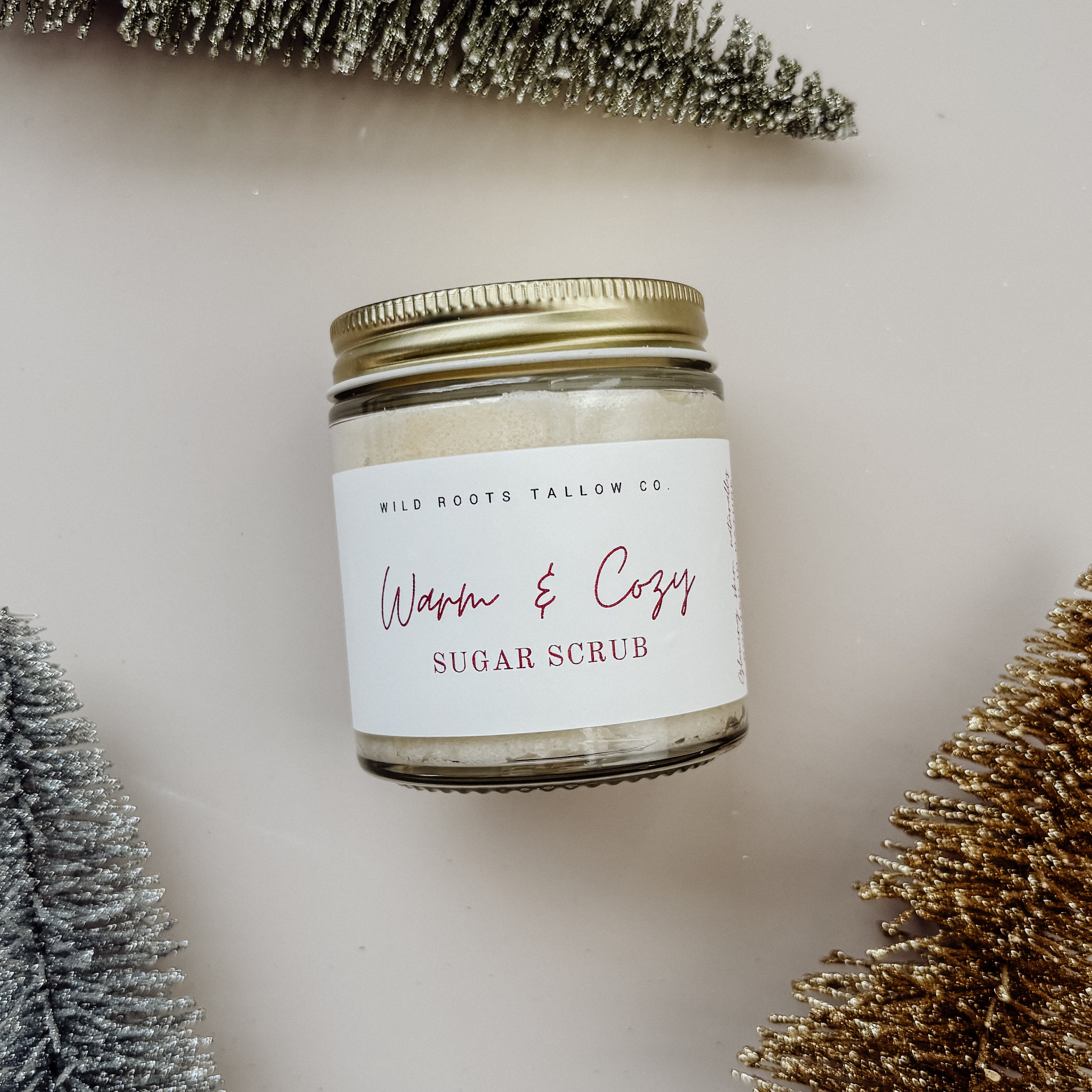 Jar of sugar scrub with decorative trees and a Christmas tree on a neutral background