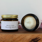 Two jars of Wild Yam Tallow Balm from Wild Roots Tallow Co on a wooden surface with a white background.