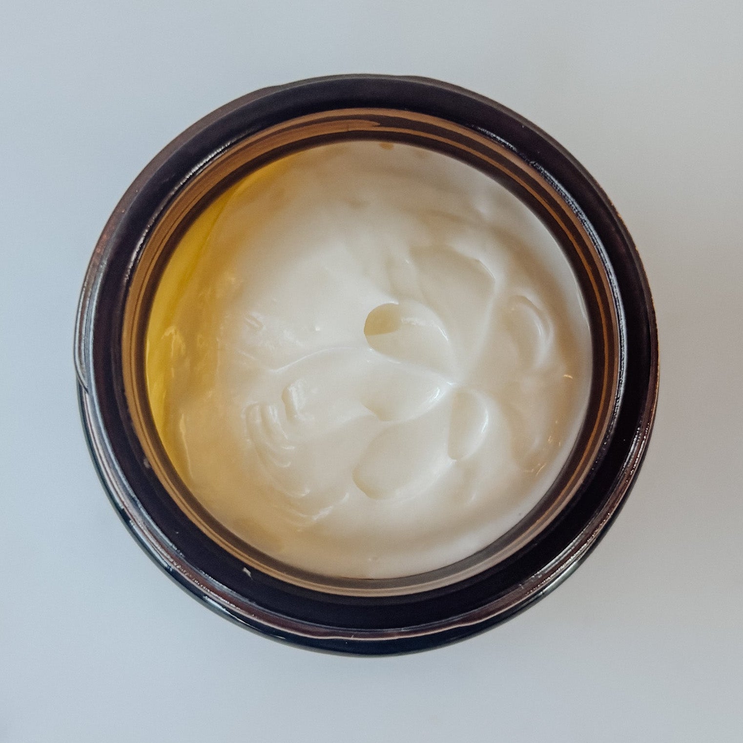 Jar of white cream on a light gray background