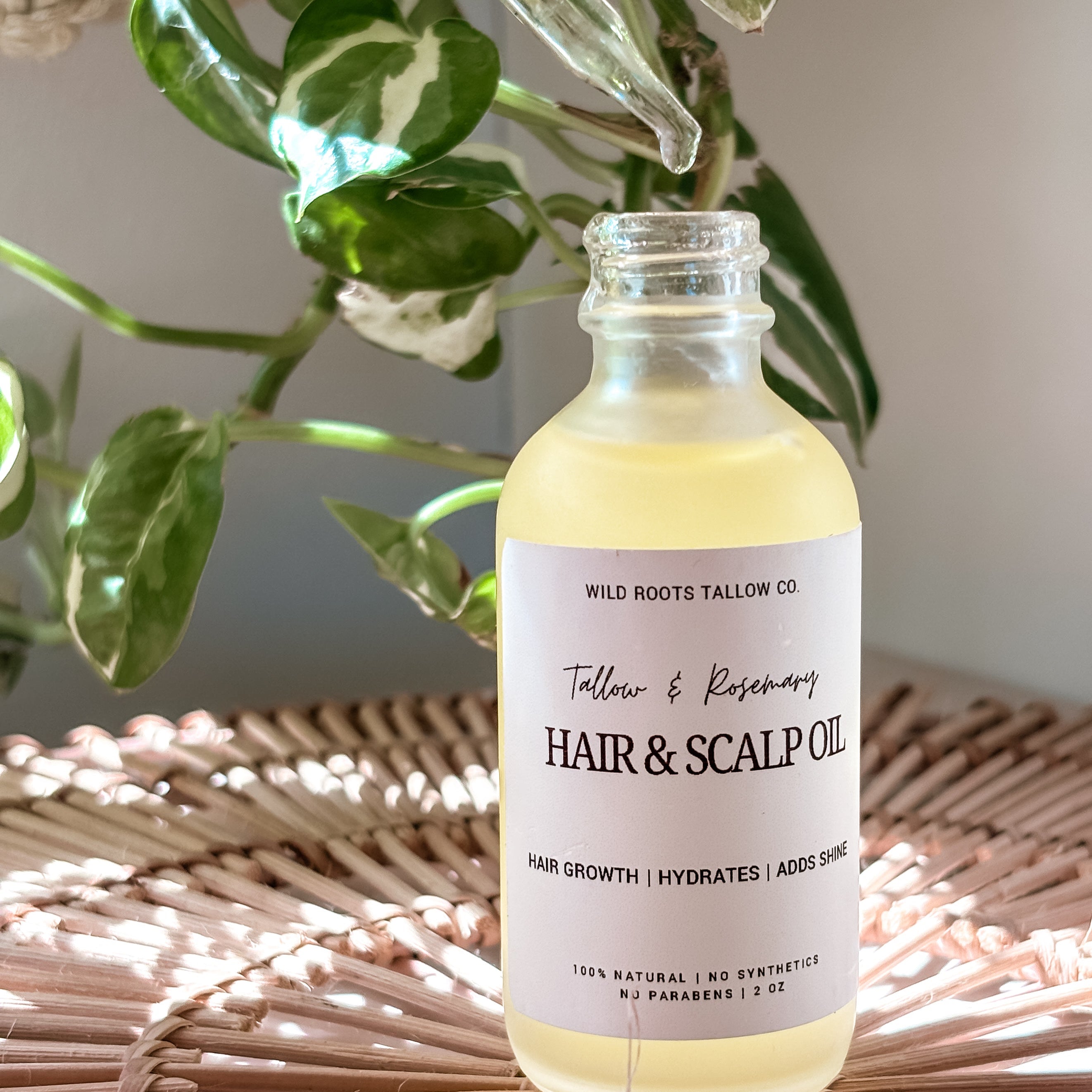 Hair and scalp oil bottle on a woven surface with plants in the background